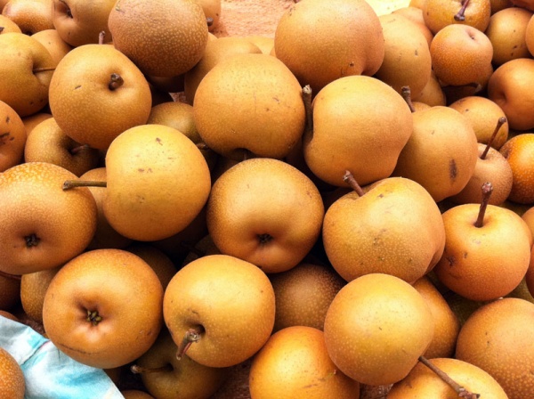 ![Hình ảnh những quả mắc cọp vỏ nâu nhám, trông mộc mạc đặt cạnh những bông hoa rừng trắng muốt]